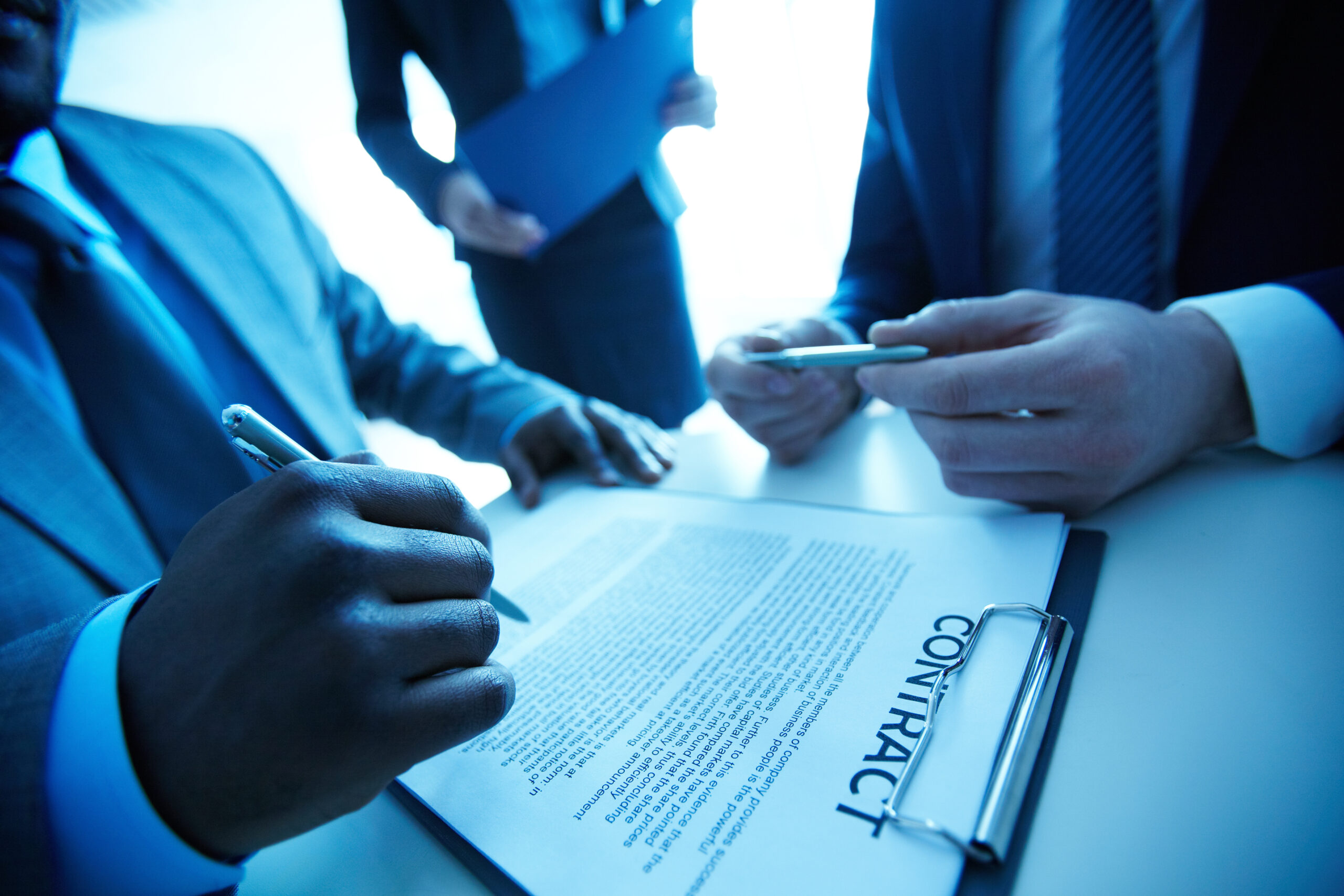 Image of contract on workplace and group of partners making decision to sign it